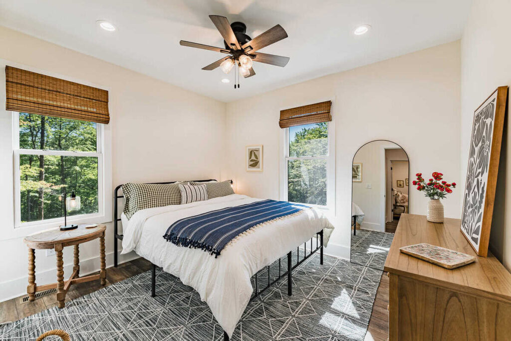 Bedroom with a black metal bed topped with gingham pillowcases and a navy and white striped coverlet.