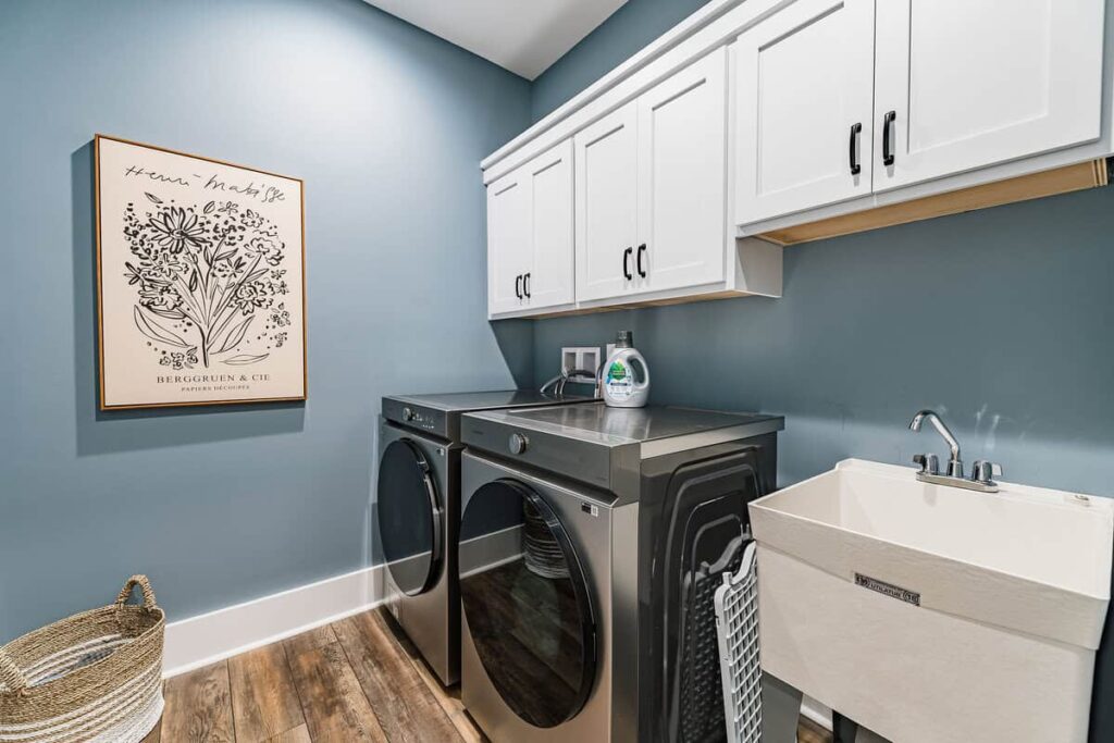 Laundry room with washer, dryer, and white cabinets.