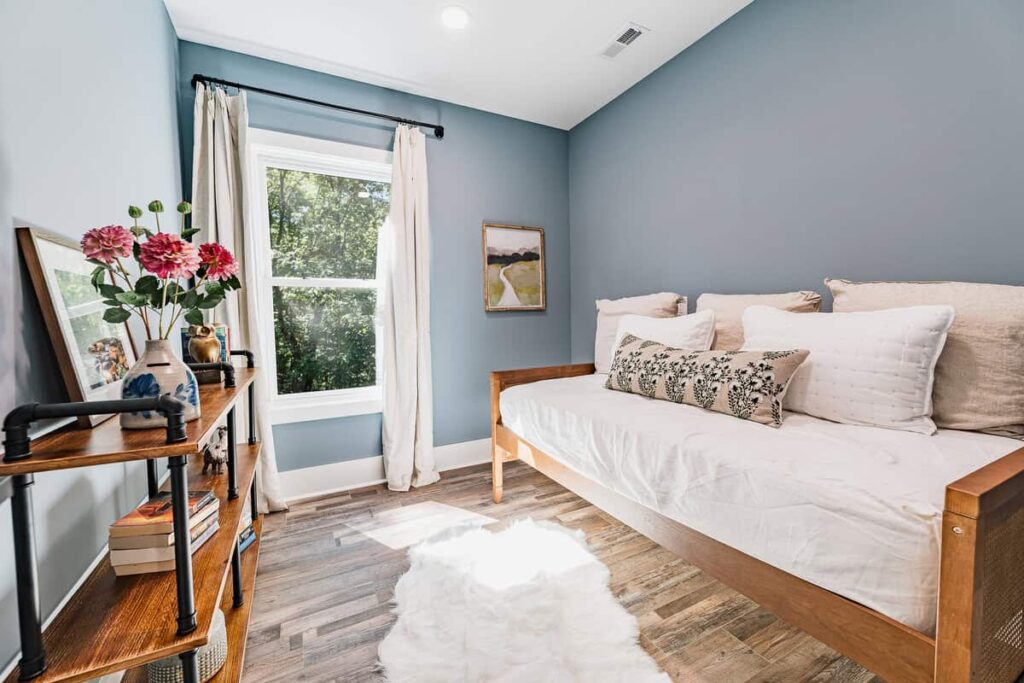 Sitting room with a wooden daybed and a wood and metal bookcase.