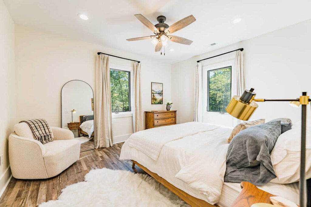 Picture of a primary bedroom, including a king bed, swivel chair, dresser, and full length mirror.