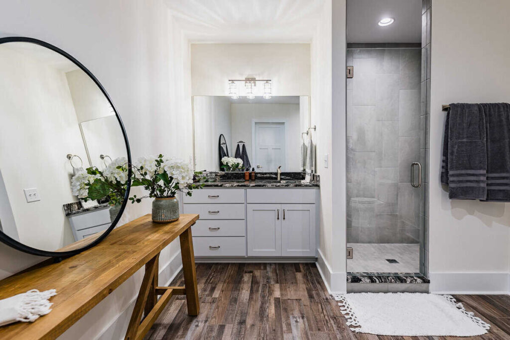 Wide shot of a bathroom with a sink, shower, and wooden console table and mirror.