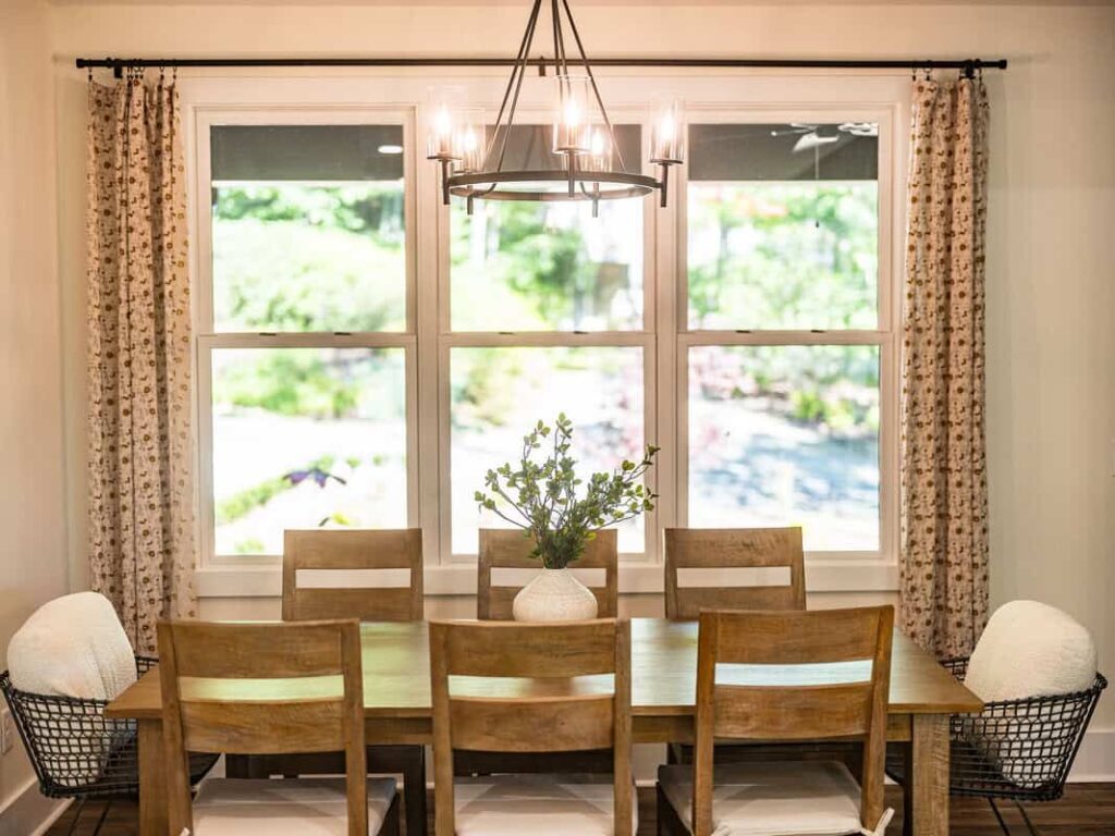 Wood dining room table with wood and metal chairs and an iron chandelier over the table.